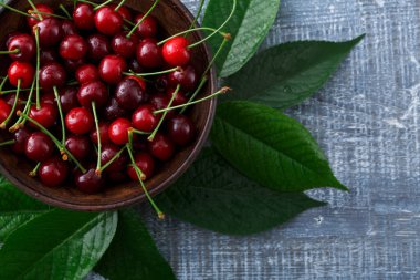 Mavi rustik ahşap üzerine yeşil yaprakları ile tatlı taze kiraz