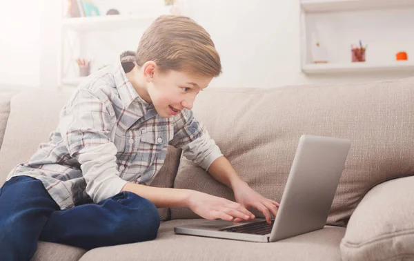 Tonårspojke med laptop på soffan hemma — Stockfoto