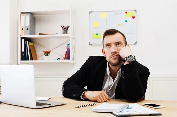 Ung uttråkad affärsman med laptop i modern vit office — Stockfoto