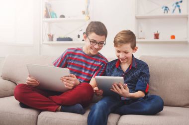 Tablet kullanarak iki genç erkek evde kanepe