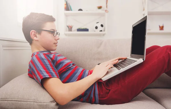Мальчик-подросток с ноутбука на диване дома — стоковое фото