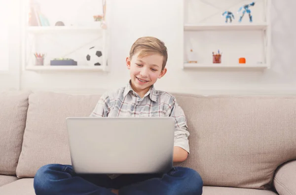 Мальчик-подросток с ноутбука на диване дома — стоковое фото