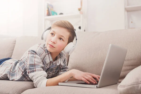 Kind jongen met behulp van de laptop op de Bank thuis — Stockfoto