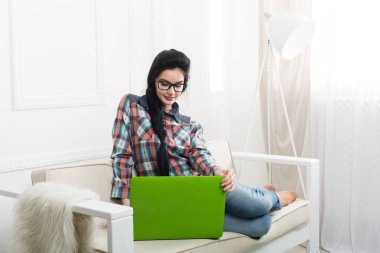 Bir dizüstü bilgisayar ile beyaz kanepe üzerinde genç kız.