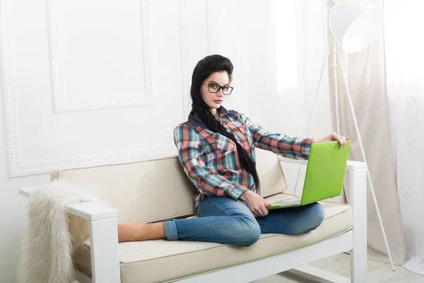 Jovem no sofá branco com um laptop . — Fotografia de Stock