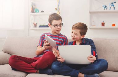 Tablet kullanarak iki genç erkek evde kanepe