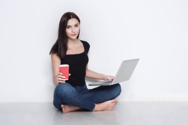 Stüdyo katta oturan dizüstü kullanan kadın