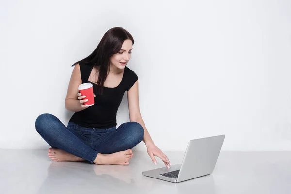 Woman using laptop sitting on the studio floor — Stock Photo, Image