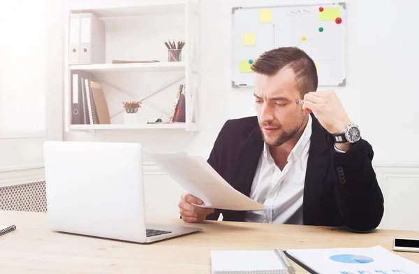 Ung koncentrerad affärsman Läs dokument i modern vit office — Stockfoto