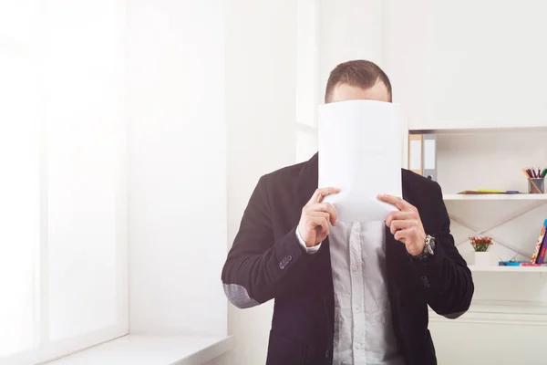 Geschäftsmann deckt Gesicht mit leerem Papier ab — Stockfoto