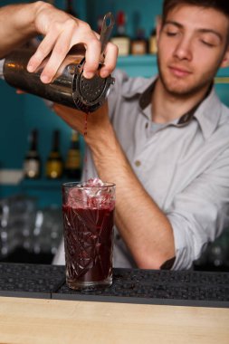 Genç yakışıklı barmen kokteyl içki cam içine dökme