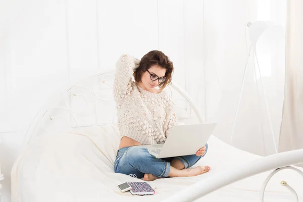 Junge Frau liest vom Laptop im Bett, hoher Schlüssel — Stockfoto