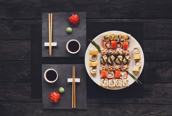 Sushi Maki Set und Rollen auf rustikalem schwarzem Holz, von oben — Stockfoto