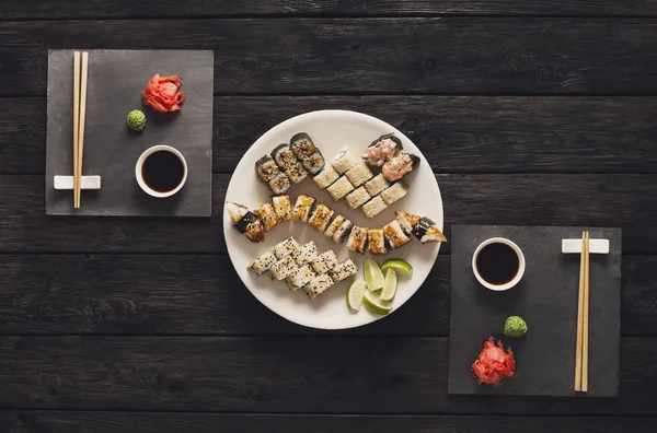 Σύνολο sushi maki και ρολά σε μαύρο ρουστίκ ξύλο, κορυφαία προβολή — Φωτογραφία Αρχείου