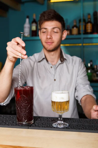 Jovem barman bonito derramando bebida de coquetel em vidro — Fotografia de Stock