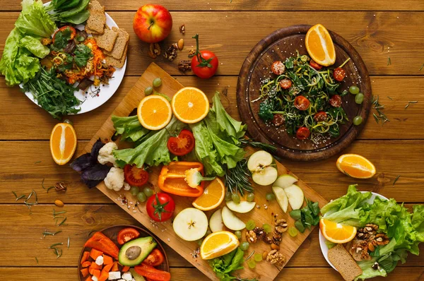 Wooden table served with cut fruits and vegetables — Stock Photo, Image