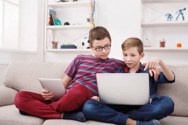 Tablet kullanarak iki genç erkek evde kanepe