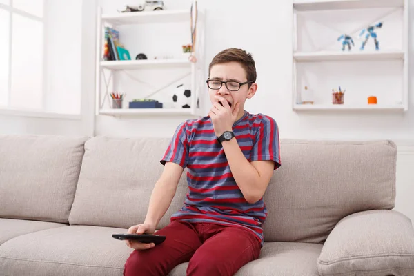 Niño viendo la televisión y buscando aburrido en el sofá en casa — Foto de Stock