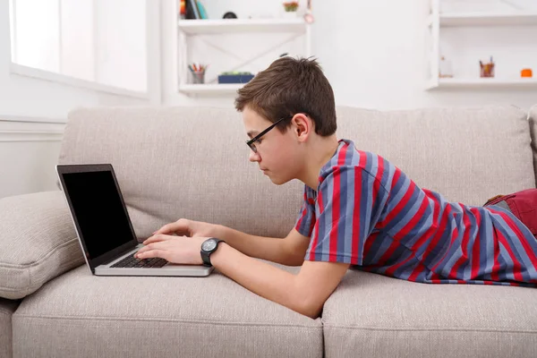 十几岁的男孩在家里的沙发上使用笔记本电脑 — 图库照片
