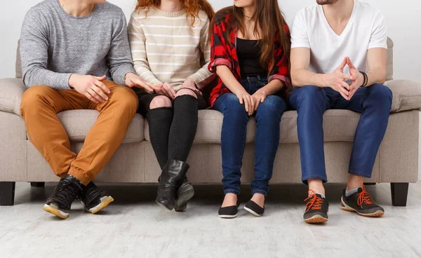 Cultivo de jóvenes amigos sentados en el sofá en el interior —  Fotos de Stock