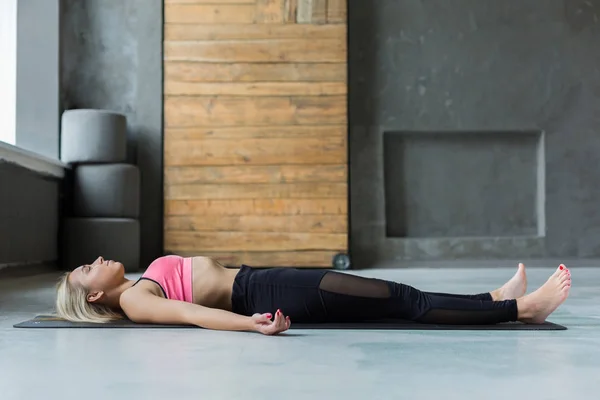 Mujer joven en clase de yoga, relajar postura cadáver meditación — Foto de Stock