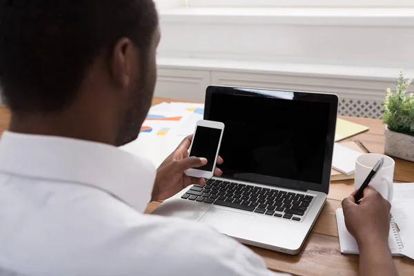Homme d'affaires afro-américain au bureau avec mobile et ordinateur portable — Photo