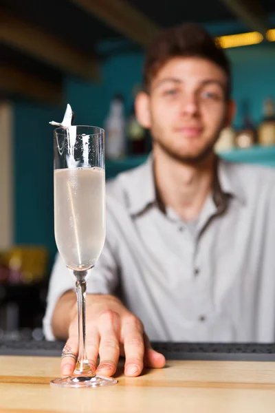 Jovem Barman oferece taça de champanhe no bar do clube noturno — Fotografia de Stock