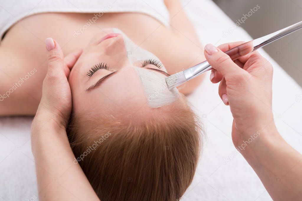 Woman gets face mask by beautician at spa