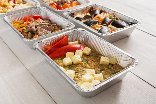 Healthy food take away in foil boxes on wood background