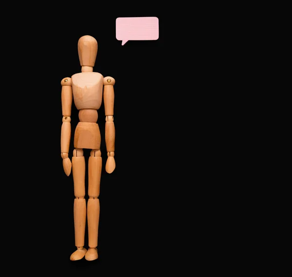 Wooden man with speech bubble, black background