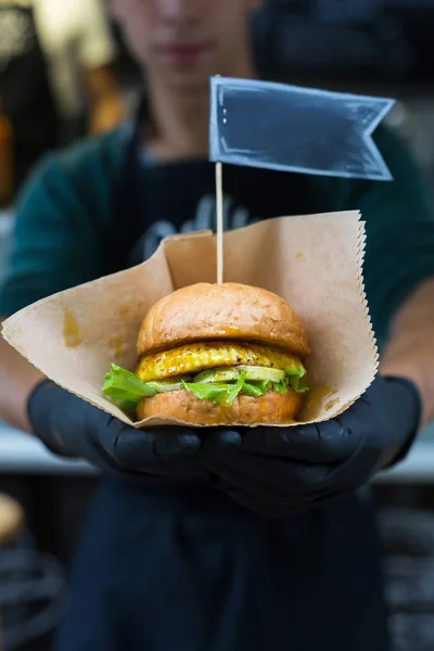 Snacks veganos - hamburguesa con etiqueta de texto en las manos —  Fotos de Stock