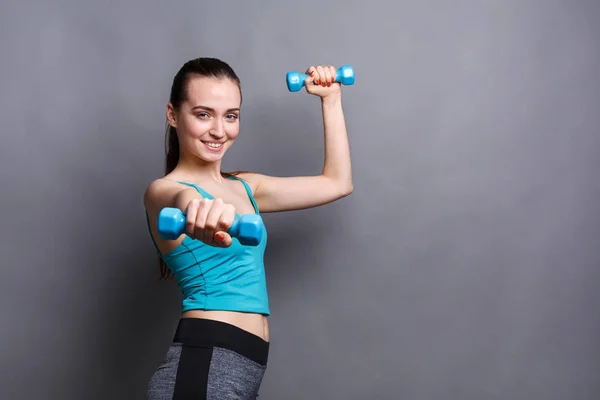 Mulher modelo de fitness com halteres no fundo do estúdio — Fotografia de Stock