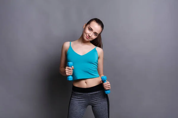Modello fitness donna con manubri sullo sfondo dello studio — Foto Stock