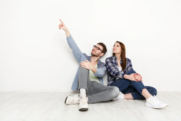 Couple moving, sitting on floor at empty room — Stock Photo, Image