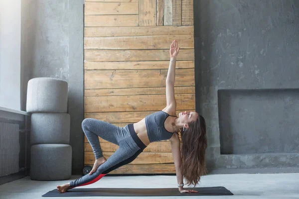 Mujer en posición de tablón lateral en clase de yoga — Foto de Stock