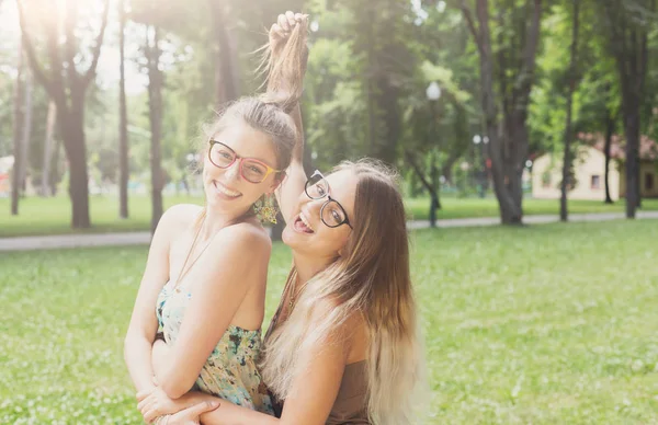 Twee gelukkige jonge meisjes omhelzen elkaar in zomer park — Stockfoto