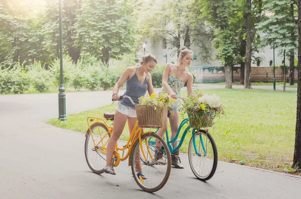 Felice boho chic ragazze si riuniscono fiori selvatici in bicicletta — Foto Stock