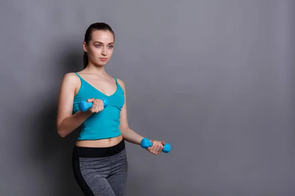 Modello fitness donna con manubri sullo sfondo dello studio — Foto Stock