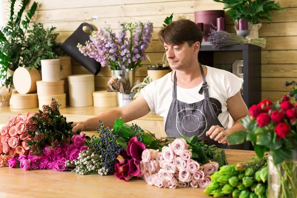 Hombre asistente en la entrega de la tienda de flores hacer ramo de rosas —  Fotos de Stock