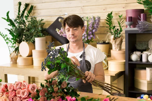 Hombre asistente en la entrega de la tienda de flores hacer ramo de rosas —  Fotos de Stock