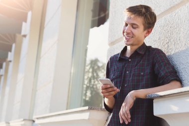 Akıllı telefon kullanan genç gülümseyen adam
