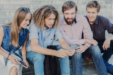 Bir grup genç insan açık havada smartphone kullanarak