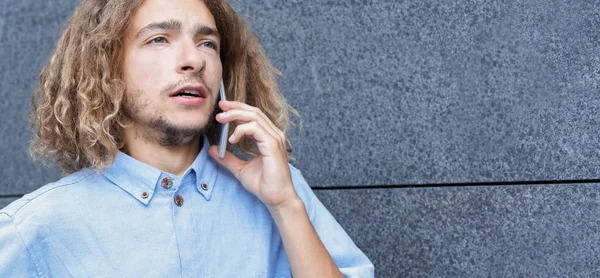 Молодий чоловік розмовляє по телефону на відкритому копіювальному просторі — стокове фото