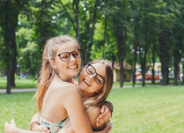 Two happy young girls hug each other in summer park — Stock Photo, Image