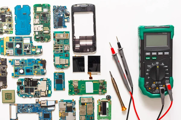 Multimeter and broken mobile electronics at repair shop