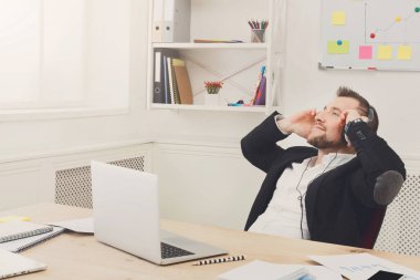 Genç rahat işadamı modern beyaz ofis müzik dinle