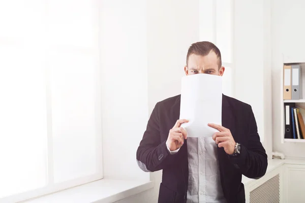Businessman covering face with blank paper