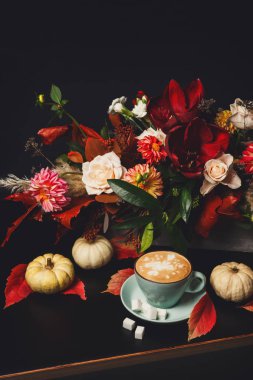 Siyah arka plan üzerine cappuccino kahve ve çiçek kompozisyon