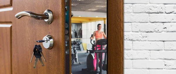 Entrada ao ginásio no clube de fitness, porta aberta com mulher em treinador elíptico — Fotografia de Stock