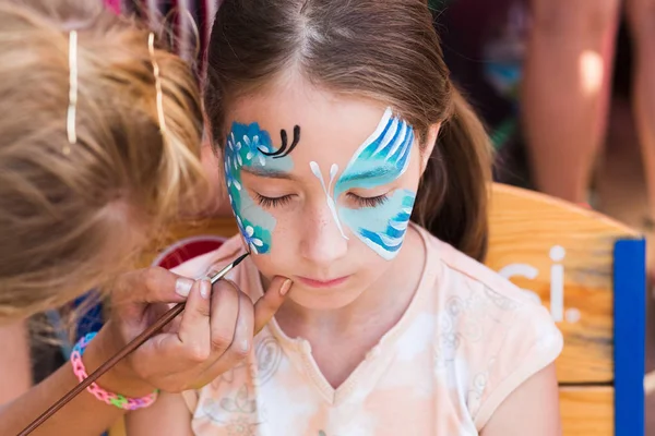 Pintura de cara de niño femenino, proceso de mariposa — Foto de Stock